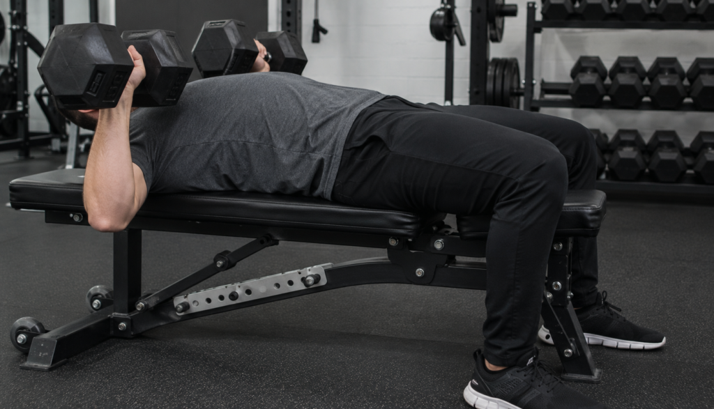 Lifter performing dumbbell bench press viewed from the side