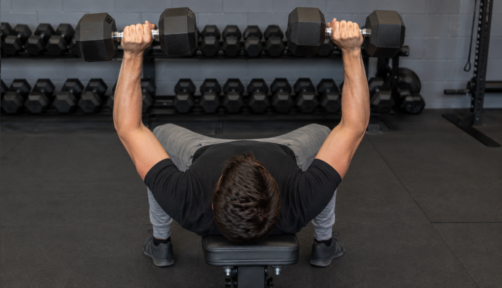Over-the-shoulder view of lifter pressing dumbbells upward