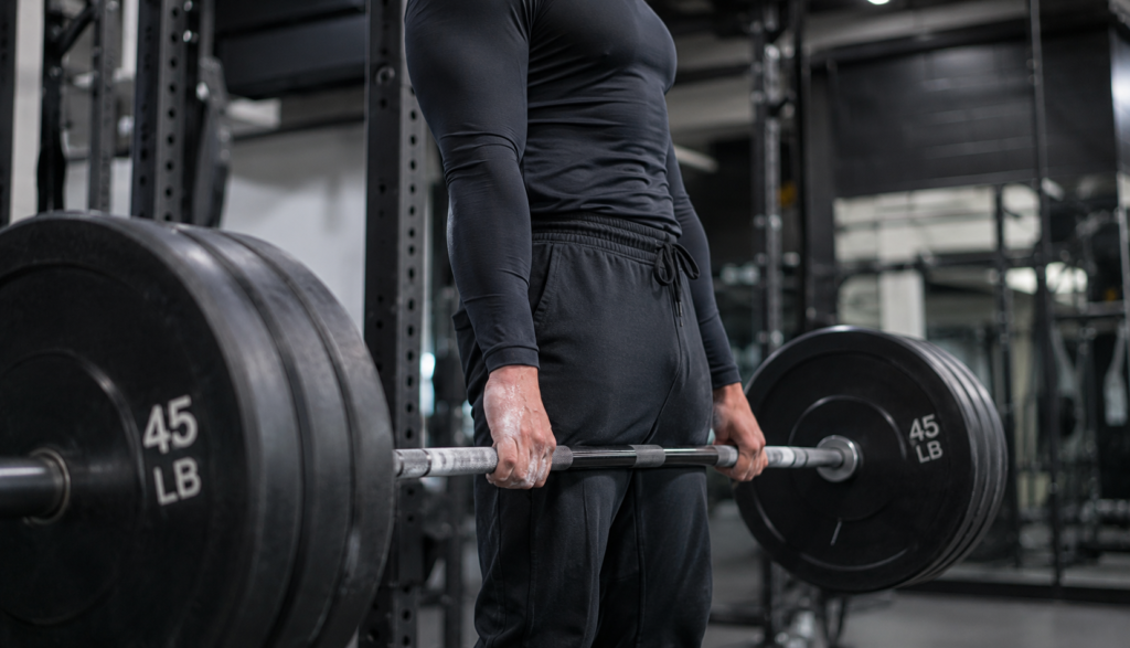 Lifter at deadlift lockout with loaded barbell, side view.