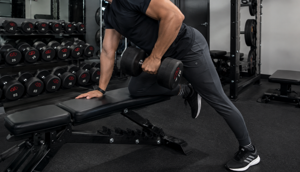 Lifter performing a dumbbell row, knee covered, face not visible
