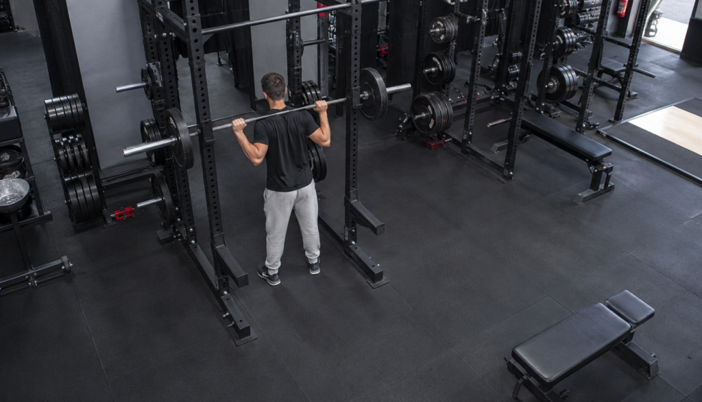 Lifter racking a barbell in a gym, wide overhead angle, no face shown