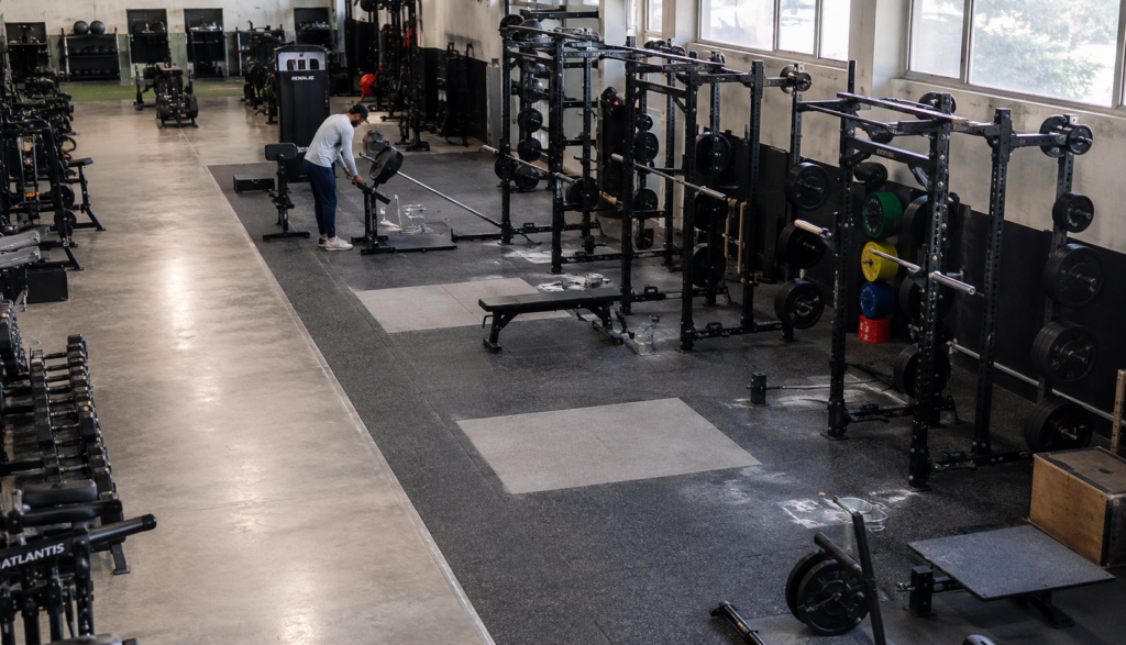 Wide gym view showing squat racks and a landmine attachment station