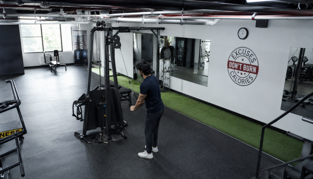 Wide gym shot of a lifter using a cable machine from above