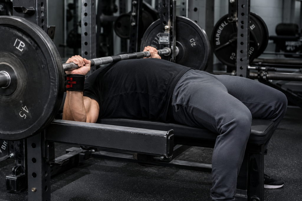 Lifter viewed from the side mid-bench-press in gym