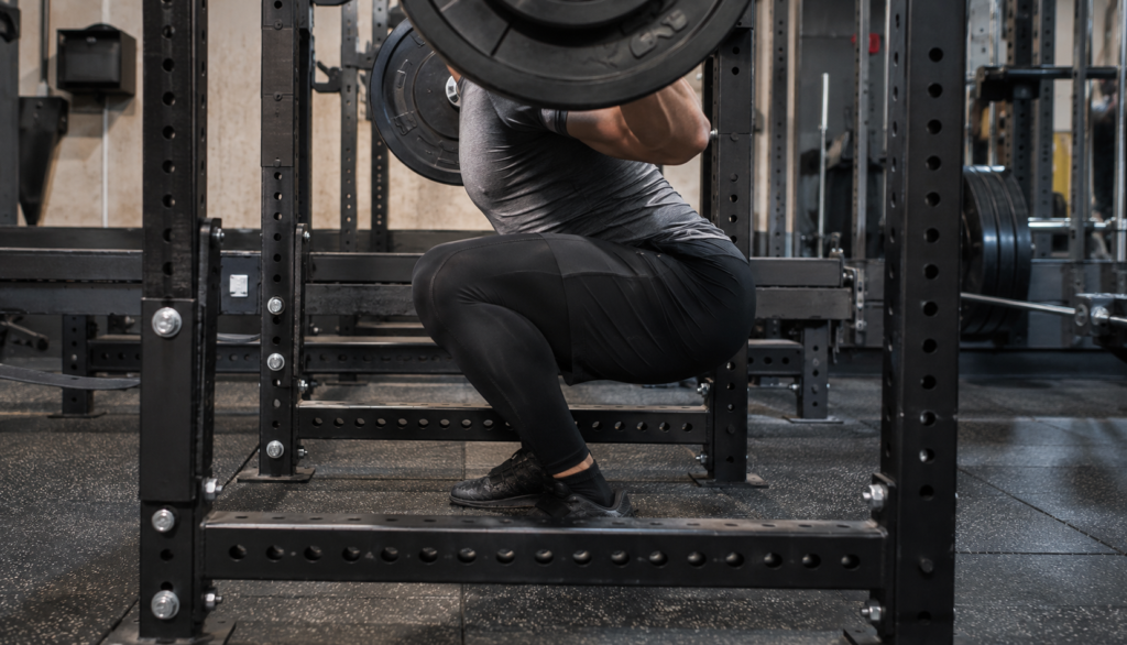 Lifter mid-squat viewed from the side inside power rack