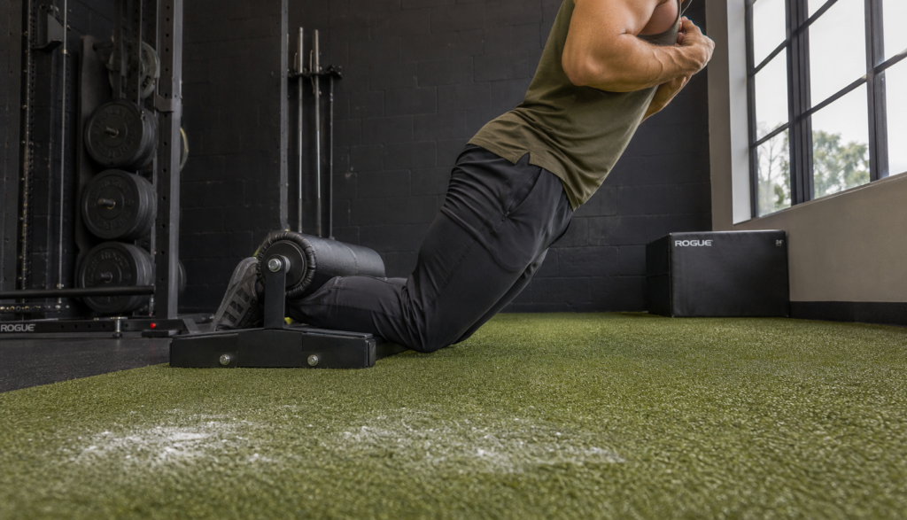 Person performing a Nordic hamstring curl exercise on turf flooring