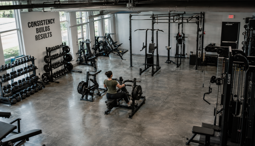 Wide gym shot of a lifter using a plate-loaded row machine