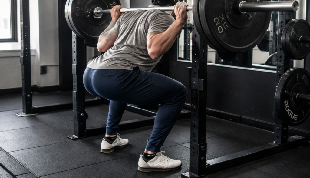 Lifter descending into full-depth back squat with loaded barbell rack