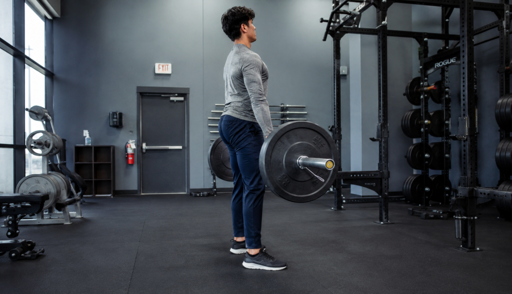 Lifter performing a barbell deadlift from a side-angle view mid-rep