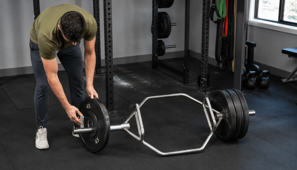 Lifter loading a trap bar with weight plates at three-quarter angle
