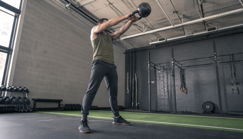 Low-angle shot of a lifter at the top of a kettlebell swing