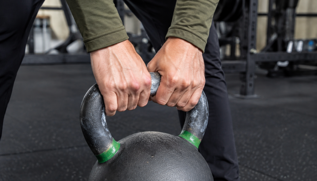 Close-up of hands gripping a kettlebell mid-swing
