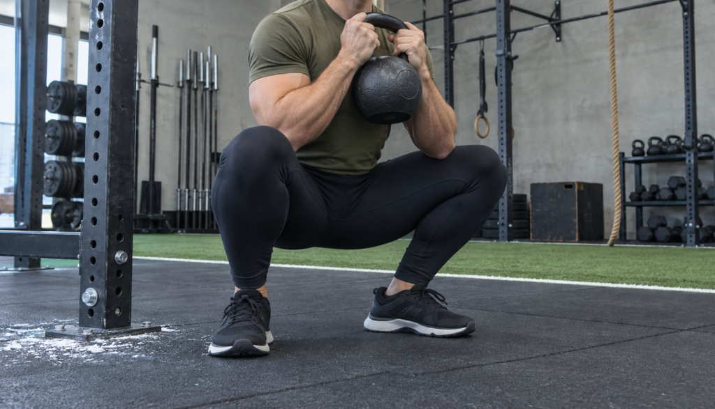Low-angle view of a male lifter performing a kettlebell goblet squat