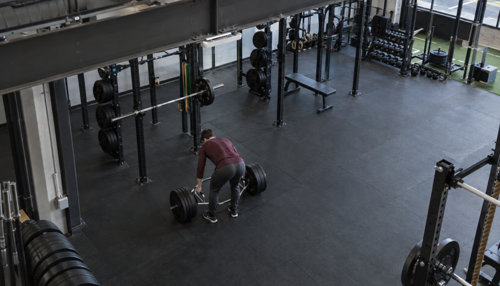 Wide gym shot of lifter racking a trap bar